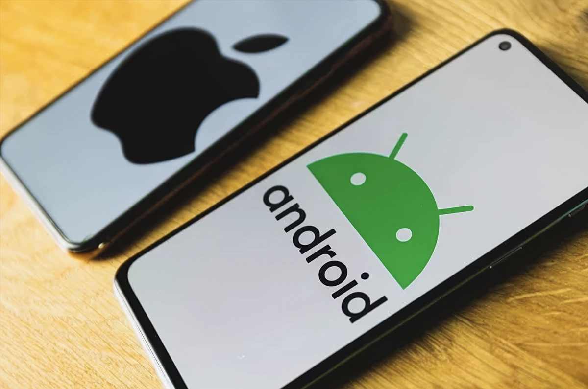 Deux smartphones sur une table, l'un avec le logo Apple, l'autre avec le logo Android.